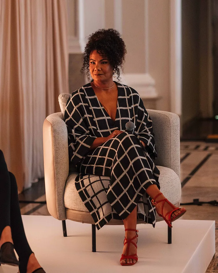 Ediane Ribeiro sentada em uma poltrona durante uma conversa em palco